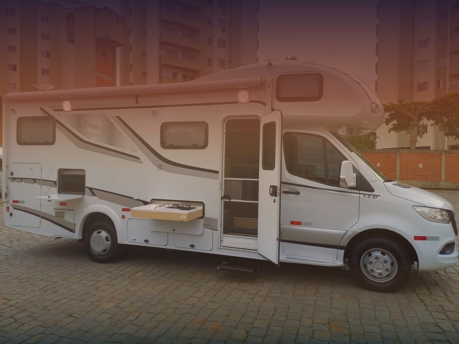 Motorhome MP Motorhomes com porta aberta, cozinha externa e mesa lateral